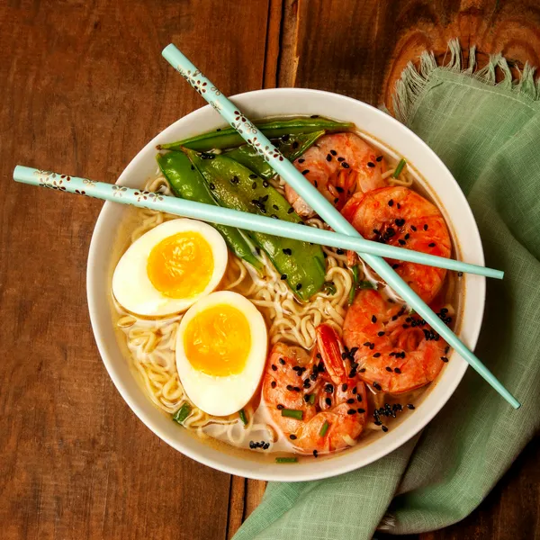 A finished bowl of phở being garnished with herbs